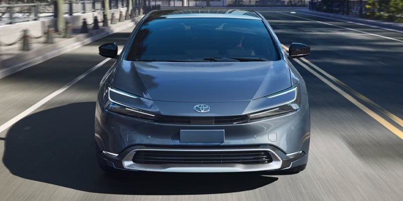 Silver Toyota sedan driving on a city street with modern styling and LED headlights.